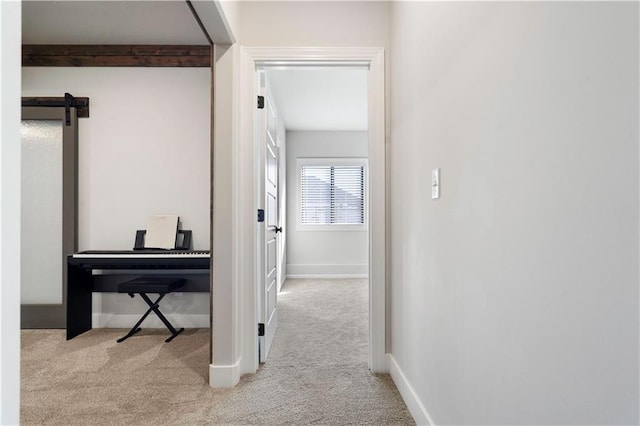 corridor featuring light carpet and a barn door