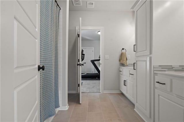 bathroom with curtained shower, vanity, and tile patterned flooring