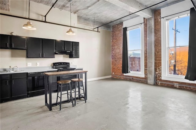 kitchen with pendant lighting, black appliances, sink, a kitchen bar, and brick wall