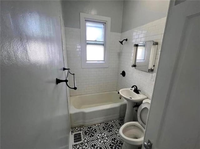 bathroom featuring tile patterned flooring, toilet, and tiled shower / bath