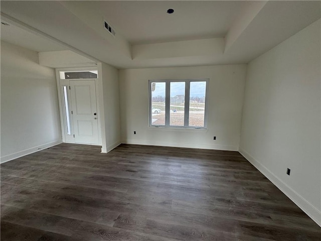 unfurnished room featuring a tray ceiling and dark wood-type flooring