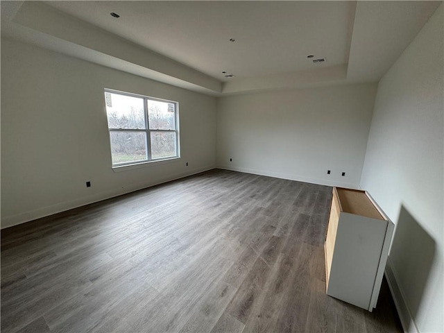 empty room with hardwood / wood-style flooring and a raised ceiling