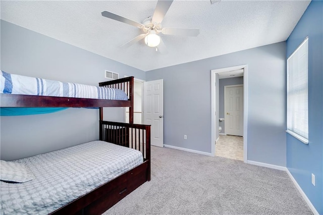 carpeted bedroom featuring ceiling fan and a textured ceiling