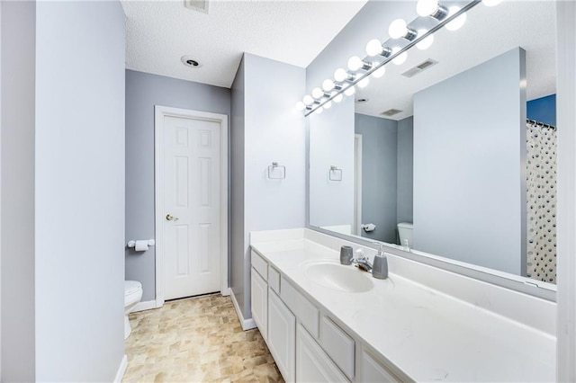 bathroom with vanity, a textured ceiling, and toilet