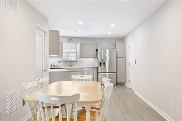 kitchen featuring sink, appliances with stainless steel finishes, gray cabinetry, tasteful backsplash, and light wood-type flooring