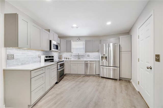 kitchen featuring appliances with stainless steel finishes, sink, gray cabinetry, and light hardwood / wood-style flooring