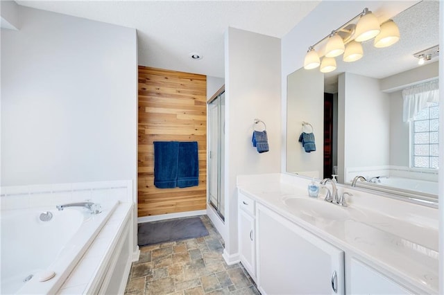 bathroom with vanity, a relaxing tiled tub, wooden walls, and a textured ceiling