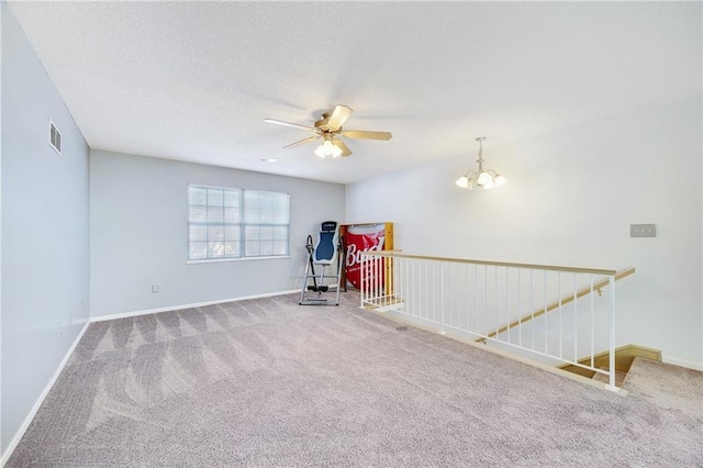 unfurnished room with carpet floors, ceiling fan with notable chandelier, and a textured ceiling