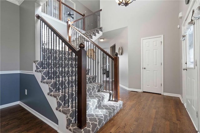 stairs with hardwood / wood-style floors and a high ceiling