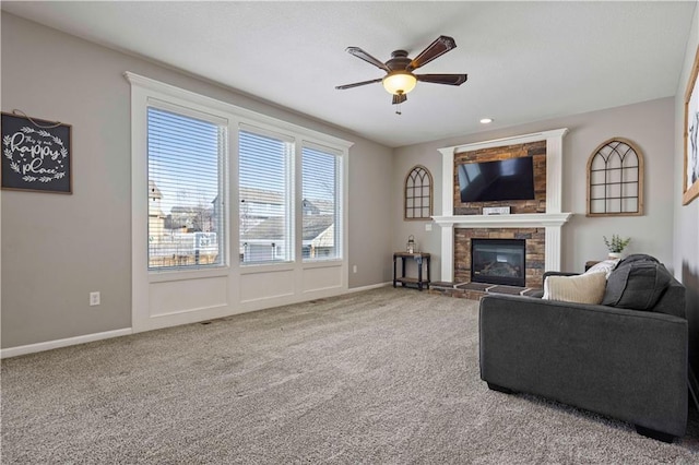 living room with a stone fireplace, carpet floors, and ceiling fan