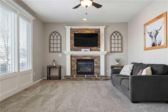 carpeted living room featuring ceiling fan and a fireplace