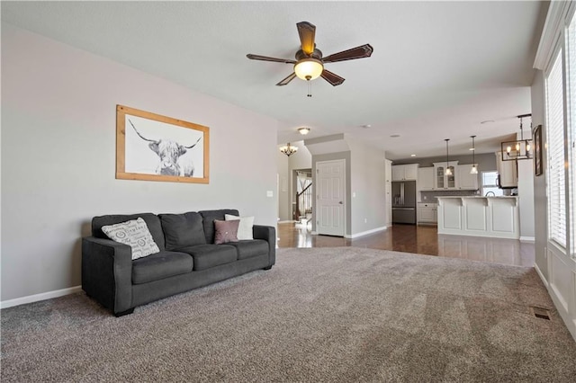 living room featuring ceiling fan with notable chandelier