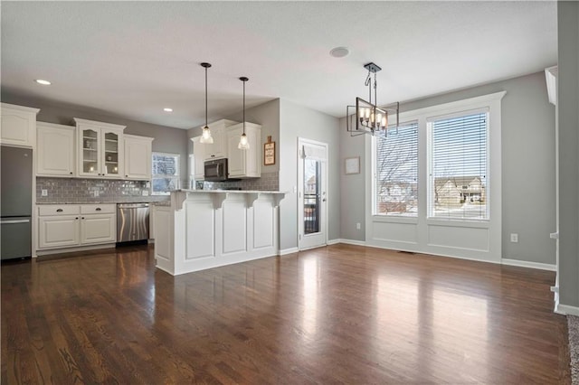 kitchen featuring tasteful backsplash, decorative light fixtures, stainless steel appliances, and white cabinets