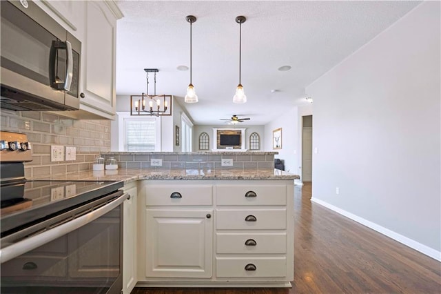 kitchen with tasteful backsplash, white cabinetry, appliances with stainless steel finishes, and light stone countertops