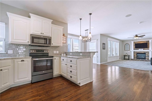 kitchen with appliances with stainless steel finishes, pendant lighting, white cabinetry, backsplash, and kitchen peninsula