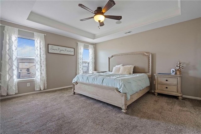 bedroom featuring ceiling fan, a raised ceiling, and multiple windows