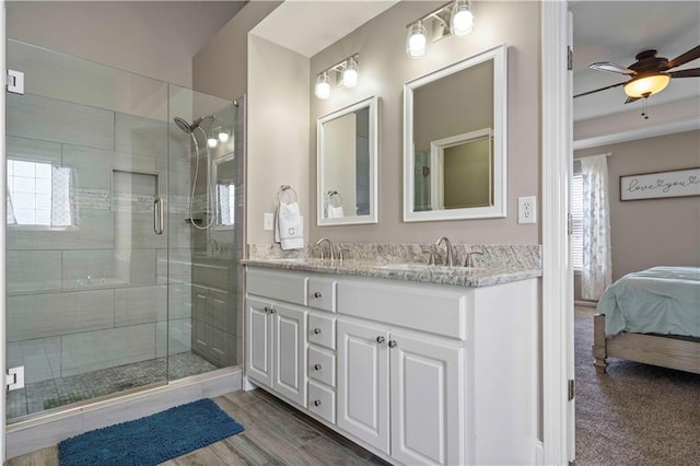 bathroom with ceiling fan, vanity, a shower with shower door, and wood-type flooring