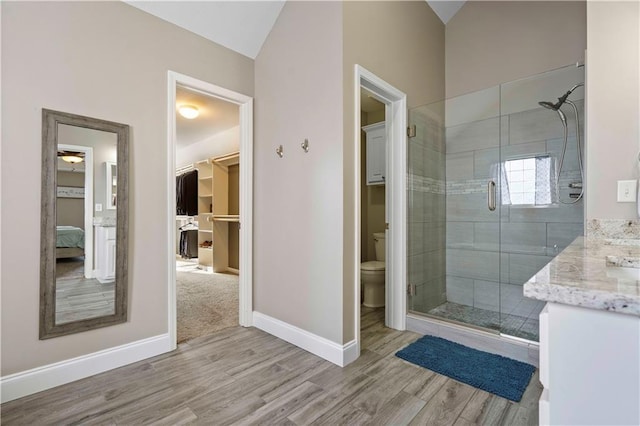 bathroom featuring vanity, hardwood / wood-style flooring, lofted ceiling, and toilet