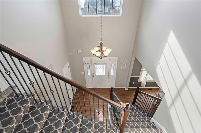 foyer featuring a towering ceiling, a wealth of natural light, a chandelier, and hardwood / wood-style flooring