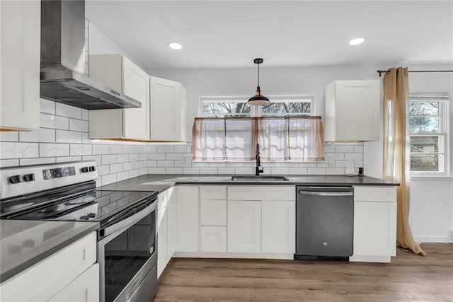 kitchen with appliances with stainless steel finishes, sink, wall chimney range hood, and white cabinets