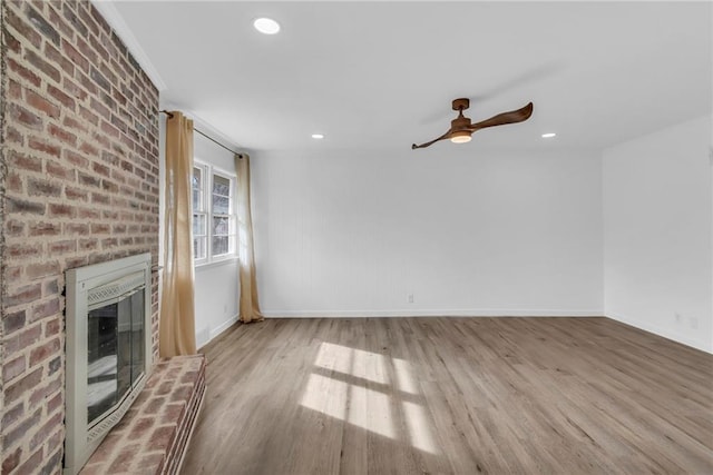 unfurnished living room with ceiling fan, ornamental molding, a fireplace, and light hardwood / wood-style floors