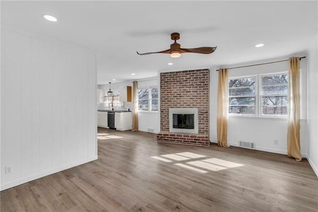 unfurnished living room featuring hardwood / wood-style flooring, ceiling fan, and a fireplace