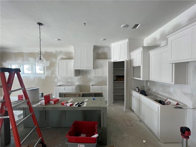 kitchen with white cabinets, hanging light fixtures, and a textured ceiling