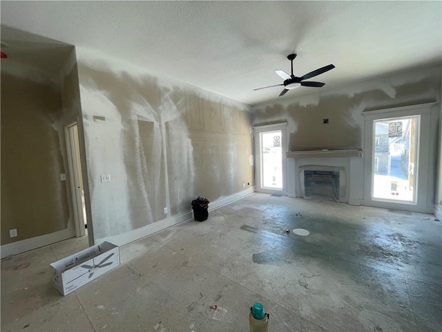 unfurnished living room featuring ceiling fan, a fireplace, and a wealth of natural light