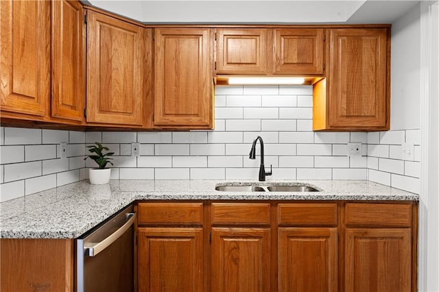 kitchen featuring stainless steel dishwasher, decorative backsplash, sink, and light stone counters