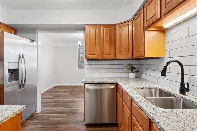 kitchen with stainless steel appliances, dark hardwood / wood-style floors, backsplash, light stone counters, and sink