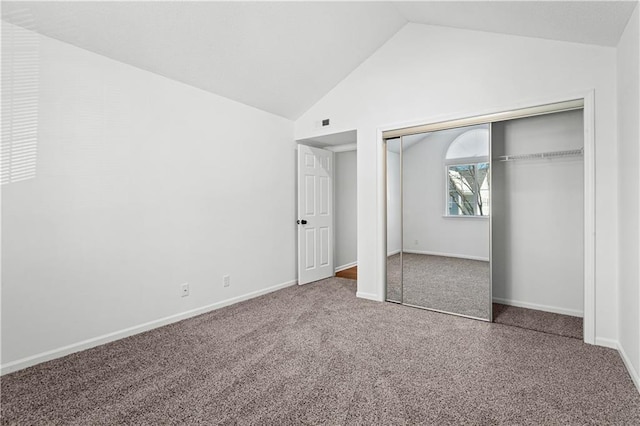 unfurnished bedroom featuring lofted ceiling, a closet, and carpet flooring