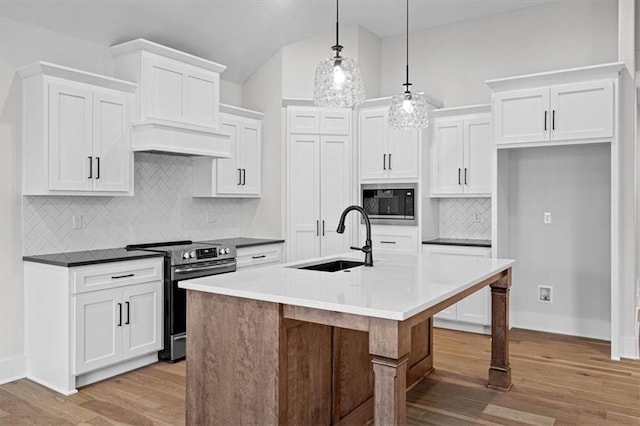 kitchen with stainless steel electric range, a center island with sink, sink, hanging light fixtures, and built in microwave