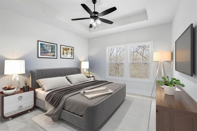 carpeted bedroom with a tray ceiling and ceiling fan