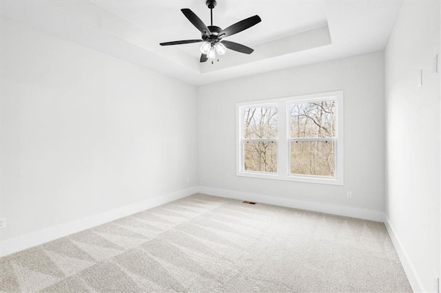 unfurnished room with ceiling fan, a raised ceiling, and carpet floors