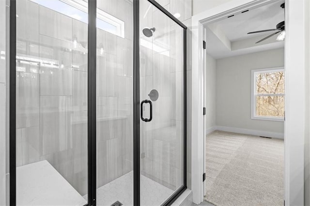 bathroom with a raised ceiling, ceiling fan, and a shower with door