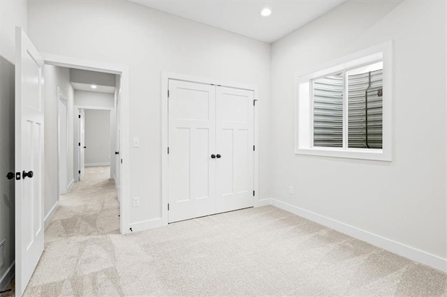 unfurnished bedroom featuring light colored carpet and a closet