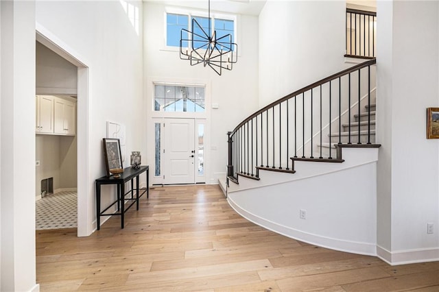 foyer entrance with a high ceiling, light hardwood / wood-style flooring, and a chandelier