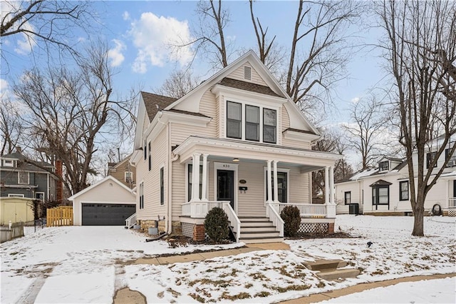 victorian home featuring a garage, covered porch, and an outdoor structure