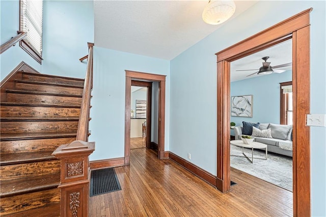 staircase with ceiling fan and wood-type flooring