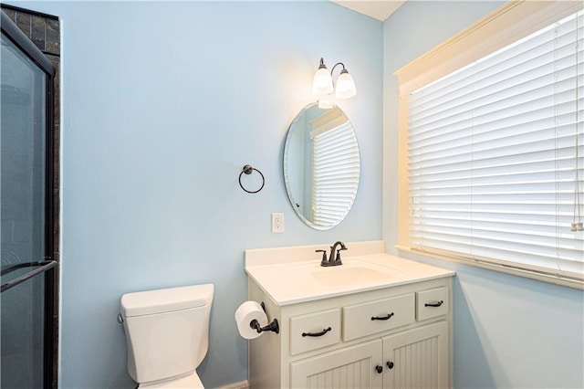 bathroom featuring toilet, vanity, and a shower with door