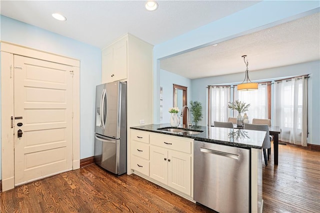 kitchen featuring white cabinetry, kitchen peninsula, sink, dark stone counters, and appliances with stainless steel finishes