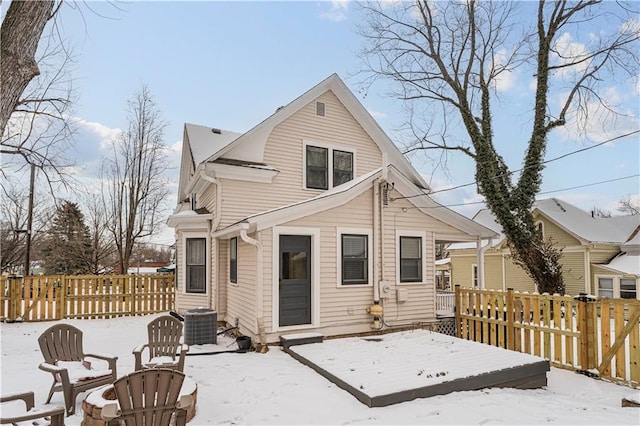 snow covered back of property with cooling unit and a wooden deck