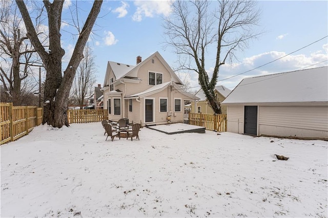 snow covered back of property featuring a fire pit