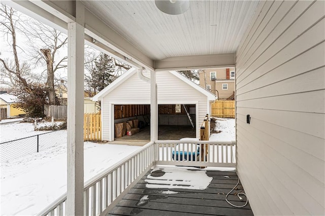 snow covered deck with a garage and an outbuilding