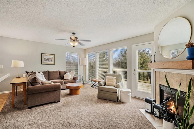 living room with ceiling fan, a tile fireplace, and a textured ceiling