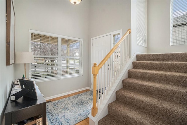 stairs with hardwood / wood-style floors and a high ceiling