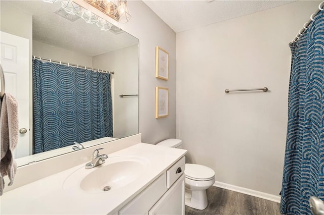 bathroom with wood-type flooring, vanity, a textured ceiling, and toilet