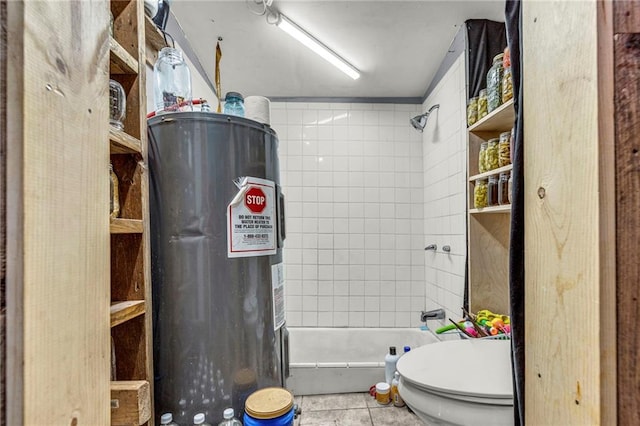 bathroom with tile patterned flooring, a tile shower, toilet, and water heater