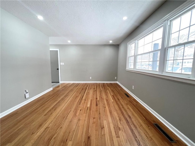 spare room featuring light hardwood / wood-style floors and a textured ceiling