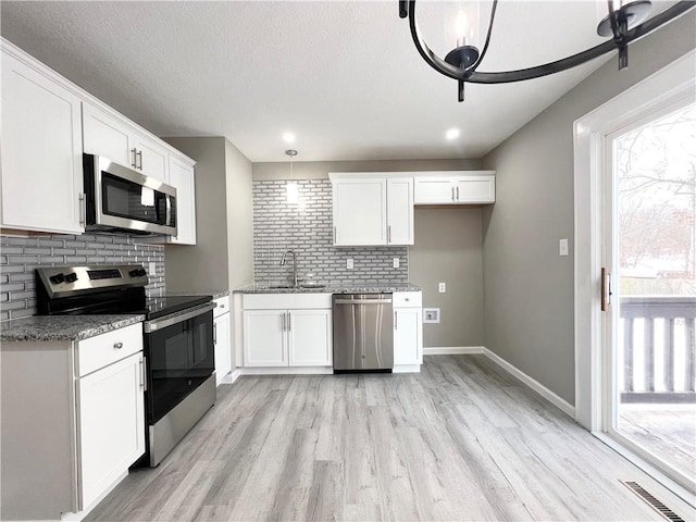 kitchen featuring white cabinets, decorative light fixtures, sink, and stainless steel appliances